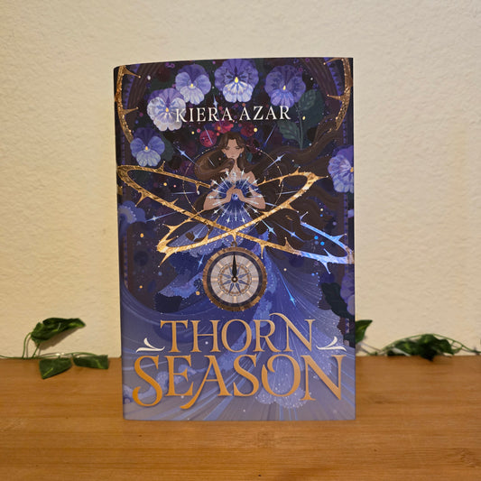 Book titled 'Thorn Season' by Kiera Azar on a surface with a neutral background