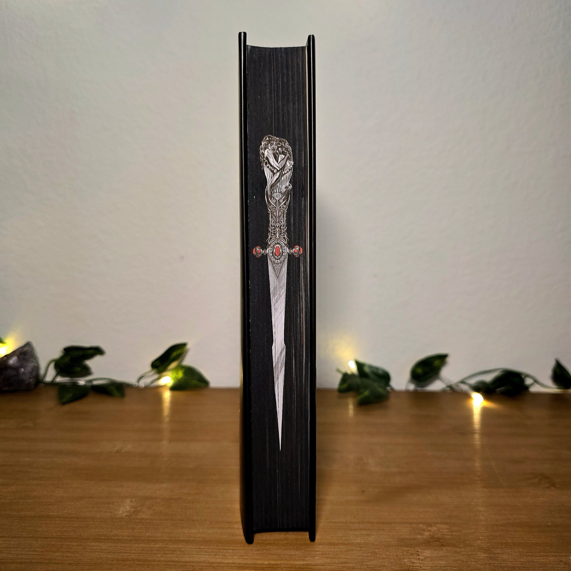 Decorative dagger with a black sheath on a wooden surface with a soft background
