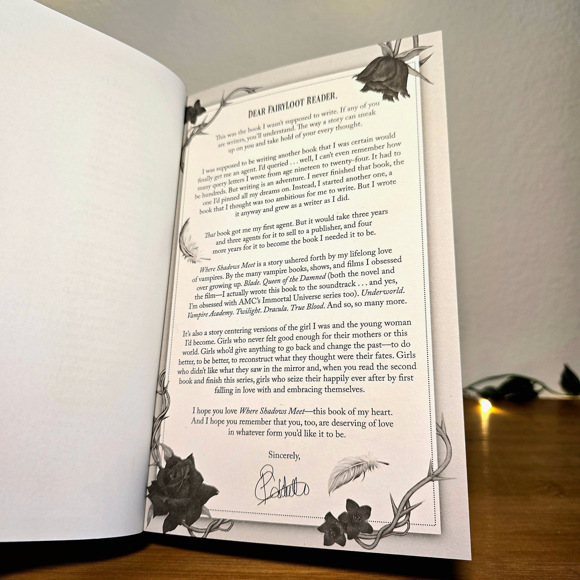 Open book with a letter and decorative text on a wooden surface