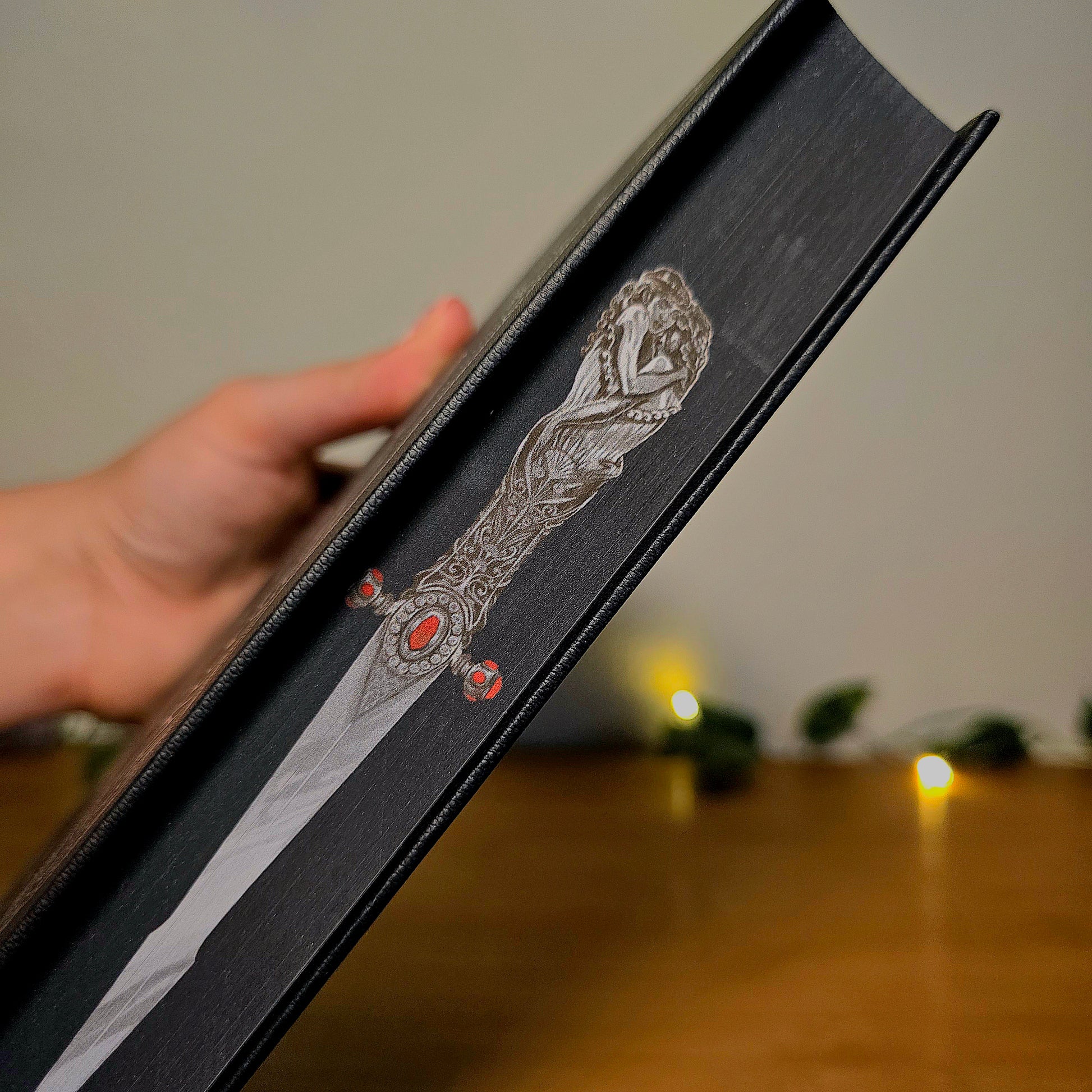 Decorative box with intricate design held by a hand on a wooden surface.