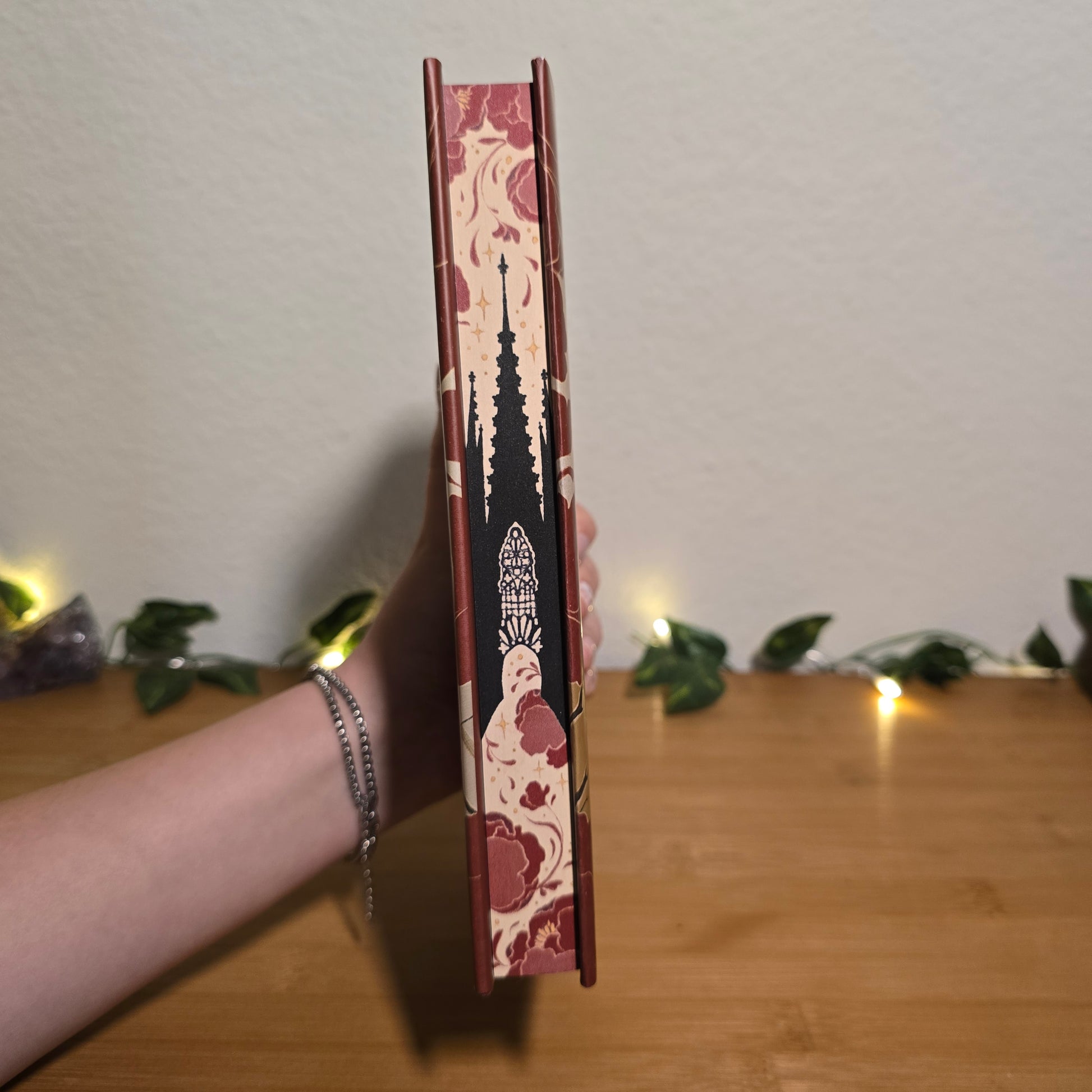 Decorative book with floral patterns held by a person against a neutral background