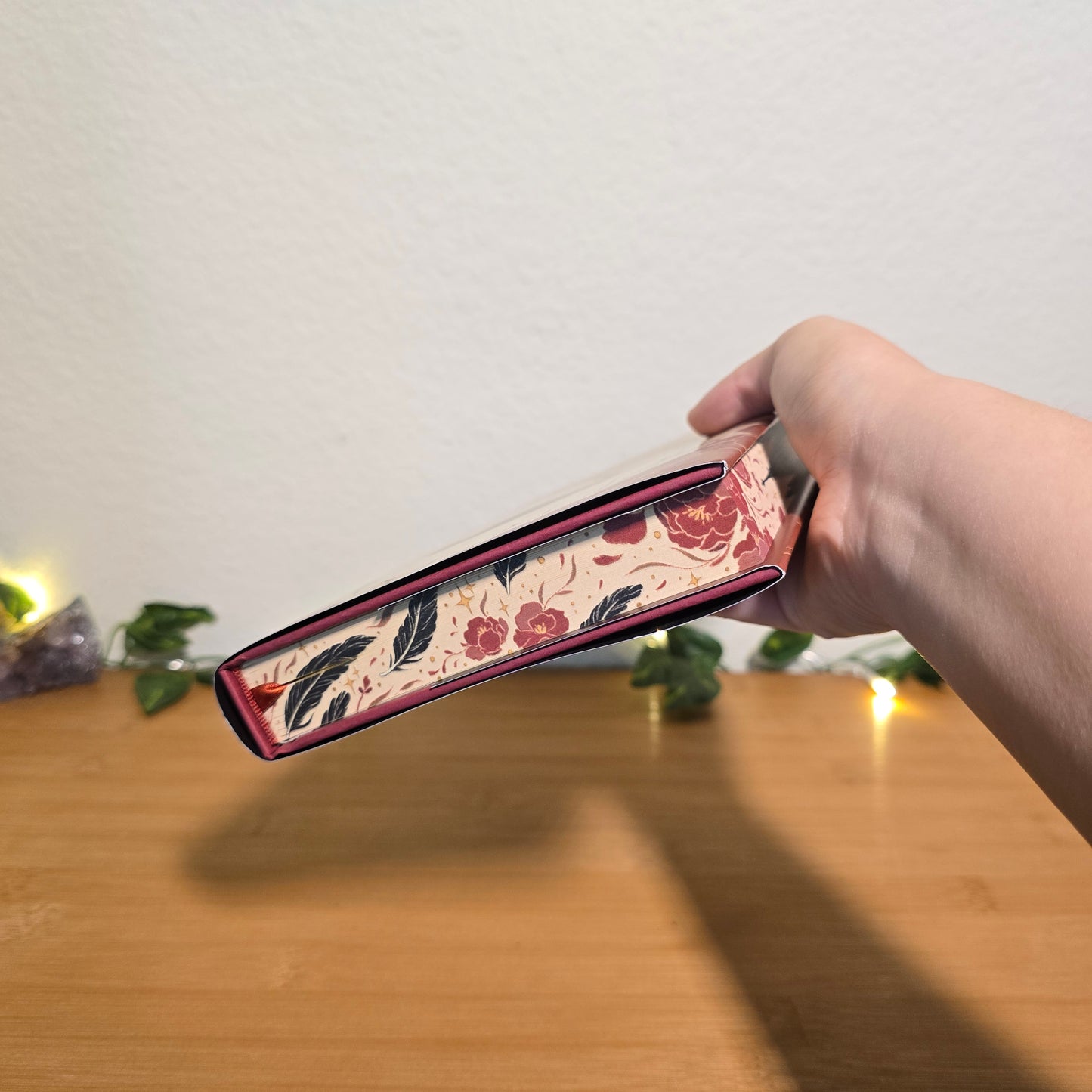 Hand holding a floral-patterned product against a neutral background