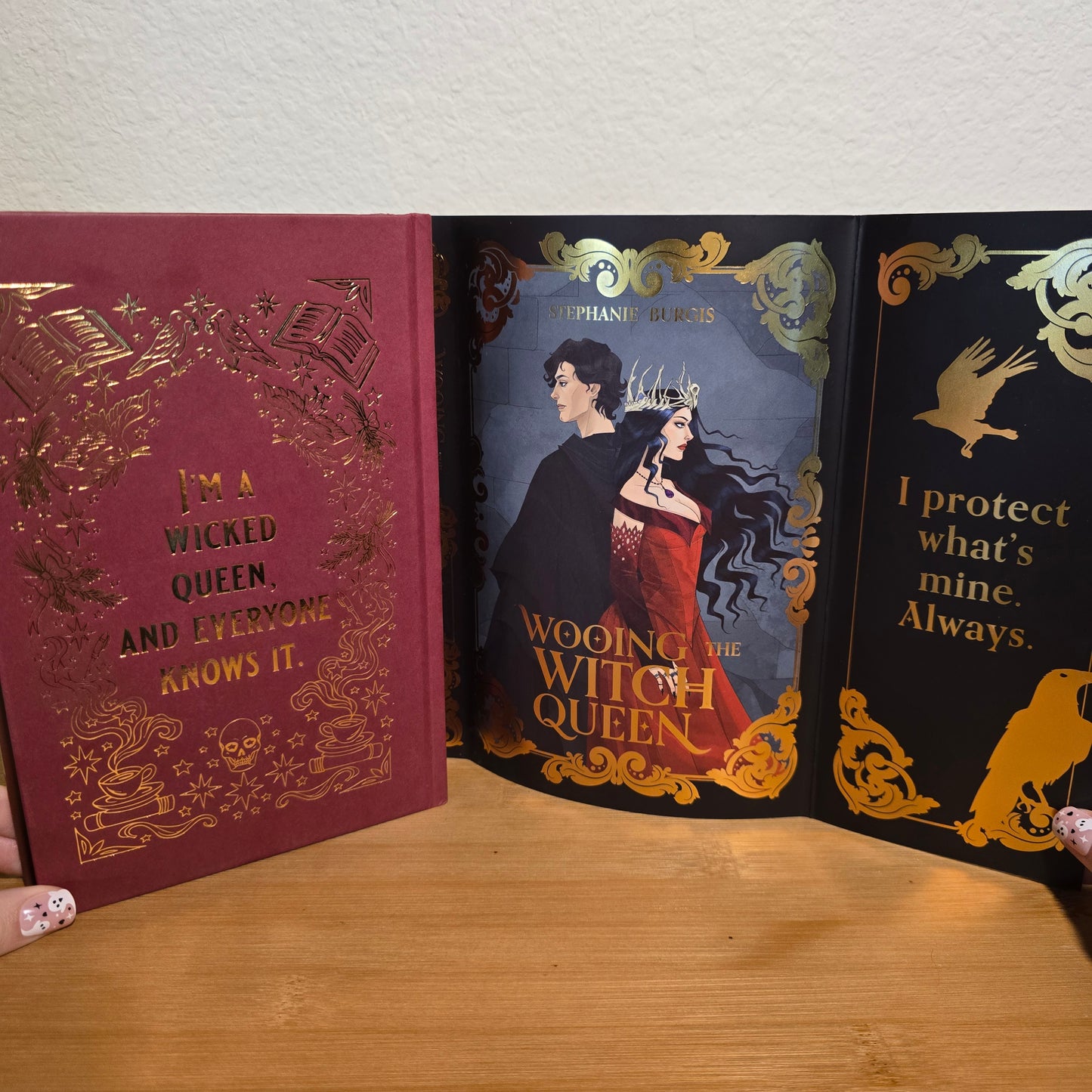 Two books titled 'Wooden Witch Queen' and 'A Wicked Queen and Everyone Else' on a wooden surface.