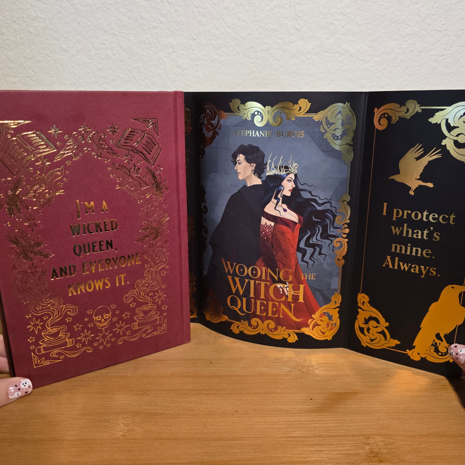 Two books titled 'Wooden Witch Queen' and 'A Wicked Queen and Everyone Else' on a wooden surface.
